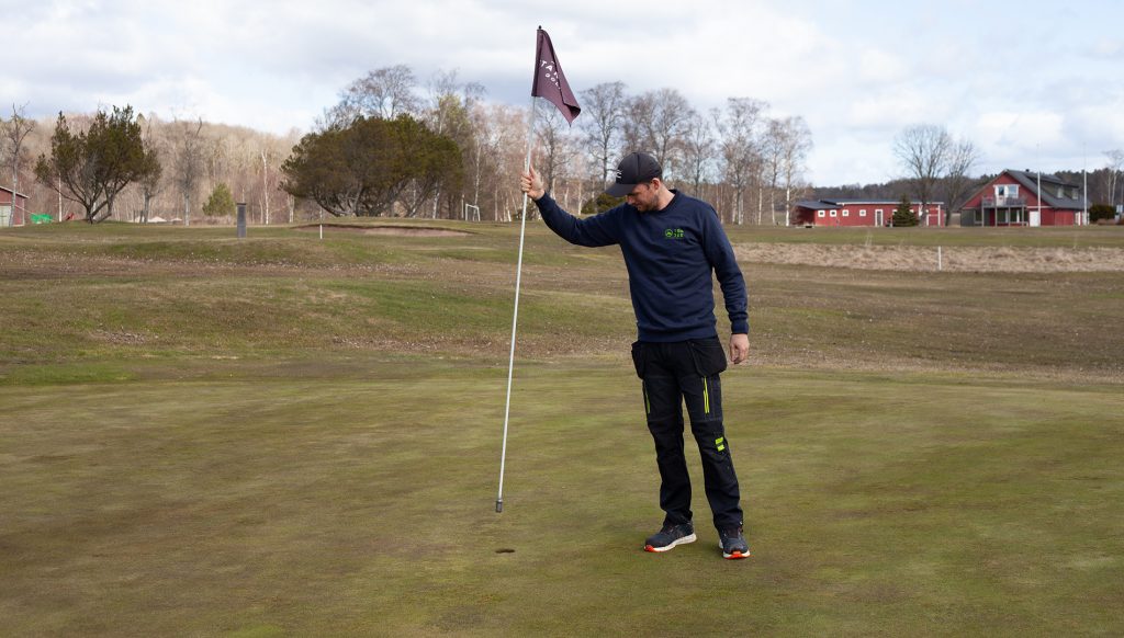 Max Collén sätter flaggorna på plats inför säsongspremiären på GolfStar Stannum.